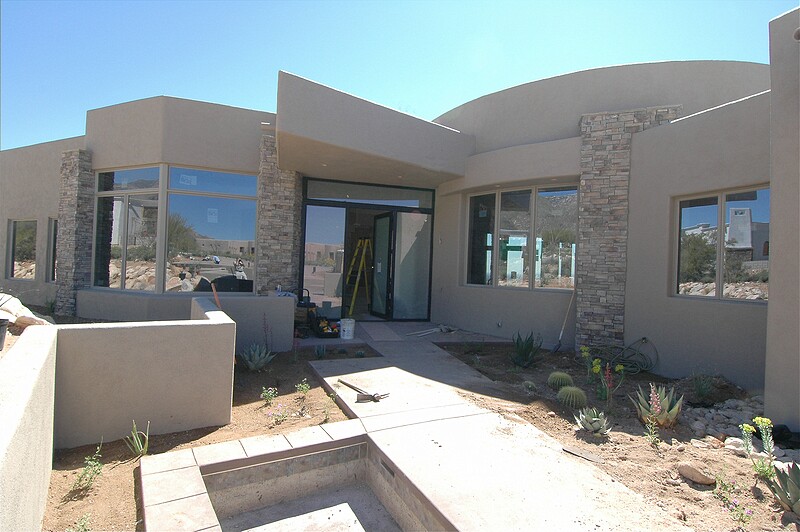 Finally the plywood has been replaced with glass in the front entry doors.  The landscapers are starting the planting in the entry courtyard.\n(March 2005)