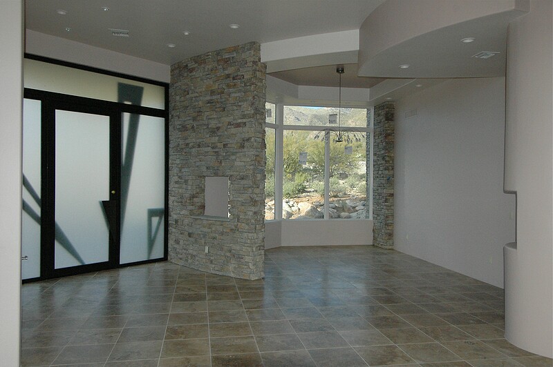 A wide angle view of the dining room and front entry foyer.  As the sun comes through the front door glass you get interesting shadows from the triangular metal overlays.\n(March 2005)